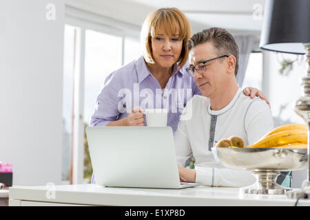 Älteres Paar mit Laptop zusammen am Tisch im Haus Stockfoto