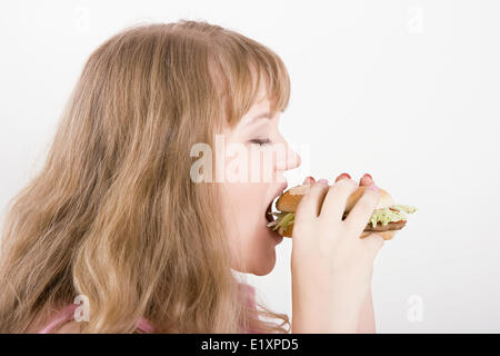 Das Mädchen beißt einen hamburger Stockfoto