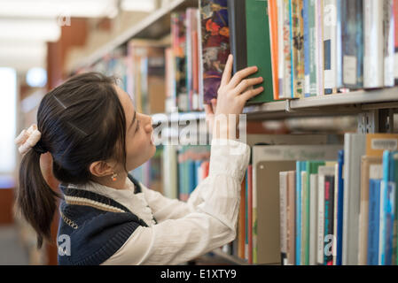 Frau, Buch zurück auf einem Bücherregal Stockfoto