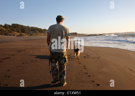 Mann zu Fuß seinen Schäferhund auf Sandstrand am Pazifischen Ozean Los Pellines chile Stockfoto