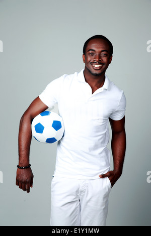 Lächelnder afrikanischen Mann halten Fußball auf grauem Hintergrund Stockfoto