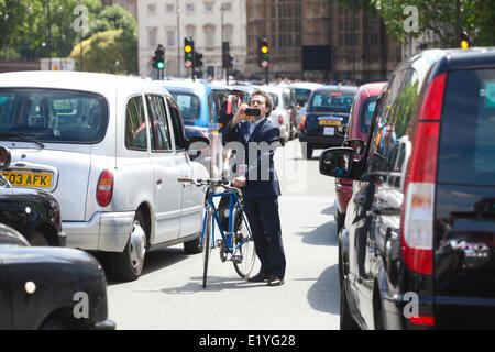 Whitehall, London, UK. 11. Juni 2014.  Ein Pendler nimmt ein Bild als Fahrer von schwarzen Londoner Taxis in der Umgebung von Trafalgar Square, die Houses of Parliament und Regierung Gebäude in Whitehall an einer Protestkundgebung gegen den Uber app-basierten Service Credit Verkehr zum Stillstand bringen: Clickpics/Alamy Live News Stockfoto