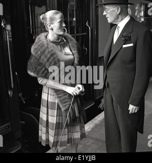 1950er Jahre historische Bild einer gut gekleideten Dame mit Pelz im Gespräch mit der Oberkellner der Pullman Eisenbahnwagen. Stockfoto