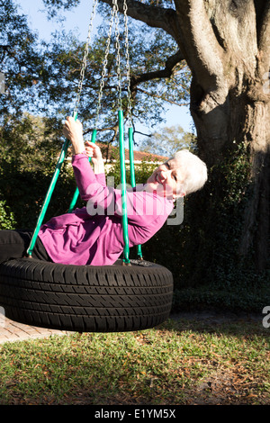 Glücklich Reife Frau spielt auf einem Reifen Schaukel, USA Stockfoto