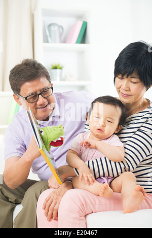 chinesische Großeltern lesen Geschichte buchen, weinende Enkelin Stockfoto