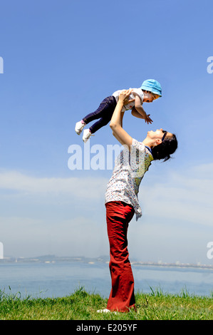 Mutter ihr Babymädchen Himmel grüne Frühling Gras aufnehmen Stockfoto