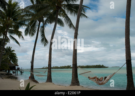 Aitutaki. Cook Island. Polynesien. Süd-Pazifik. Zwei Touristen, die Ruhe in einer Hängematte am Strand des Hotel Aitutaki Lago Stockfoto