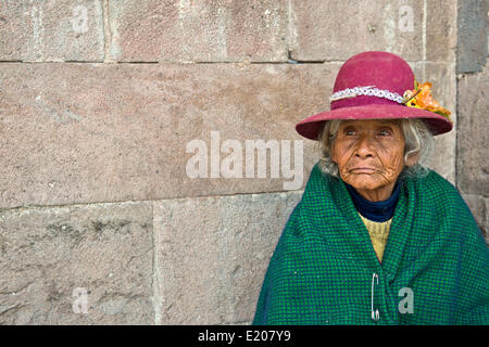 Portrait einer älteren Frau in traditioneller Kleidung der Quechua-Indianer sitzen auf dem Boden vor einem Inka-Wand Stockfoto