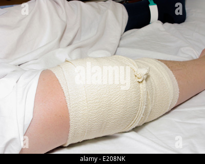 Mann mit einem bandagierten Knie & Bein nach einer Knieoperation im Krankenhaus Stockfoto