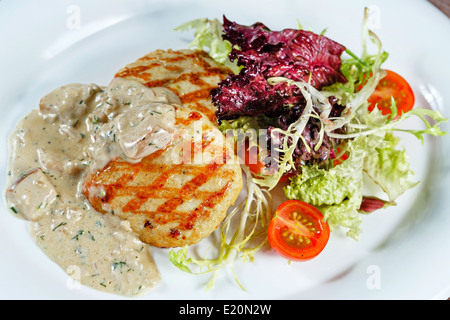 Türkei-Schnitzel mit Gemüse und Pilzsauce serviert auf einem weißen Teller in einem restaurant Stockfoto