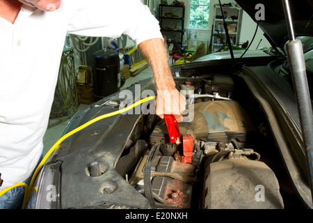 Mann mit Jumper-Kabel über die Klemmen der Batterie im Auto Stockfoto