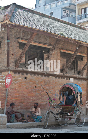 Zwei Männer, die Messer auf der Straße in Kathamdu, Nepal neben Mann schlafen im Rikscha schärfen Stockfoto