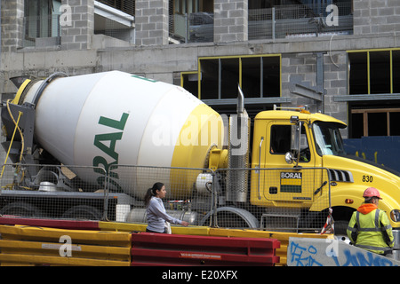 asiatische Frau vorbeigehen Fertigmischung Beton geliefert durch Boral, auf einer Baustelle in Chippendale, Sydney, Nsw, Australien Stockfoto