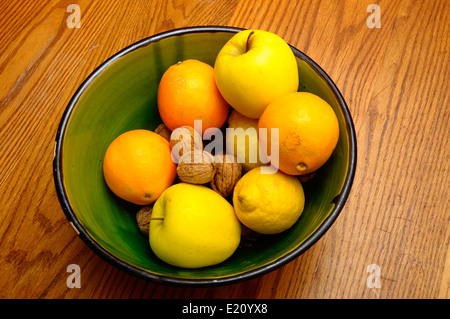 Einige französische Winter Obst, Apfel, Orange, Nüssen, Zitronensaft in einer grünen Schale auf Holztisch Stockfoto