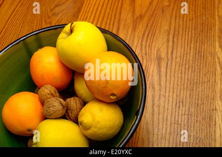 Einige französische Winter Obst, Apfel, Orange, Nüssen, Zitronensaft in einer grünen Schale auf Holztisch Stockfoto