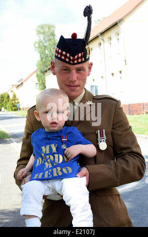 Bad Fallingbostel, Deutschland. 12. Juni 2014. Eine 19 Jahre alte Soldat des 4. posiert Battalion The Royal Regiment of Scotland mit seinen 15 Monate alten Sohn nach dem Besuch von Prinz Philip, Duke of Edinburgh an St. Barbara Basis in Bad Fallingbostel, Deutschland, 12. Juni 2014. Der kleine Junge Verschleiß ist ein Hemd, das 'My Daddy My Hero' liest. Prinz Philip seinen Vater mit einer Medaille für seinen Einsatz in Afghanistan ausgezeichnet. Foto: HOLGER HOLLEMANN/Dpa/Alamy Live News Stockfoto