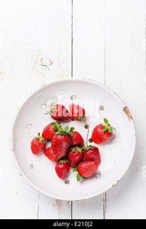 Erdbeere in Vintage Keramik Sieb auf weißem Holz Hintergrund Stockfoto