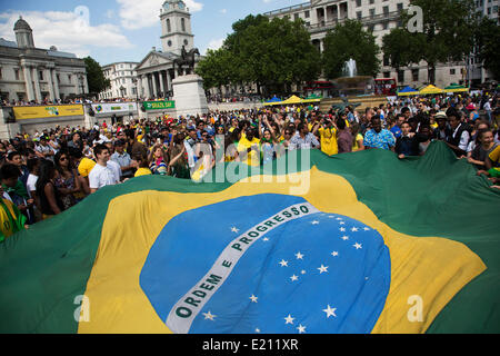 London, UK. Donnerstag, 12. Juni 2014. Riesen Flagge ist zwischen den Corwd statt. Brasilianer zu sammeln für die Brasilien-Day Feierlichkeiten in Trafalgar Sq. Eine Versammlung zu Beginn der FIFA WM 2014 in Brasilien zu feiern. Feiernden singen und tanzen und spielen Fußball-Spiele und das alles in gelb grün und Blau der brasilianischen Flagge. Bildnachweis: Michael Kemp/Alamy Live-Nachrichten Stockfoto