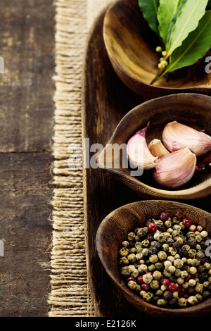 Holzschalen mit frischen Kräutern und Gewürzen (Knoblauch, Pfeffer, Lorbeer) Stockfoto