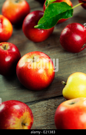 rote Äpfel mit Blättern auf Holztisch Stockfoto