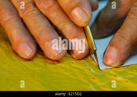 Nahe der alten bis mans Hände gelb Leder mit scharfem Messer schneiden Stockfoto