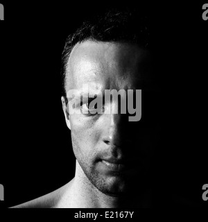 Junge ernsthafte kaukasischen Mann Closeup Portrait auf schwarzem Hintergrund Stockfoto