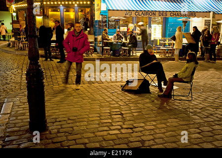 Ein Mann zeichnet ein Porträt des jungen Passanten in eine typische Nacht-Szene von Paris Stockfoto