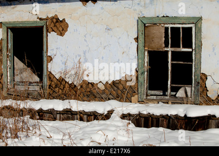 Schnee bedeckt Haus Verslumung Fenster Ziegel gebrochen Stockfoto
