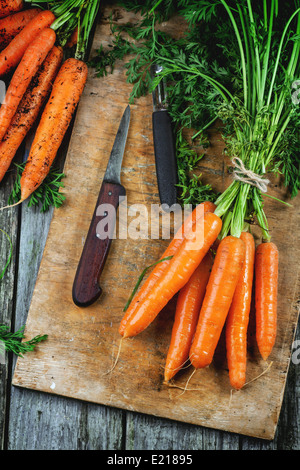 Reihe von frischen Karotten mit Vintage Messer auf alten Schneidebrett. Ansicht von oben. Stockfoto