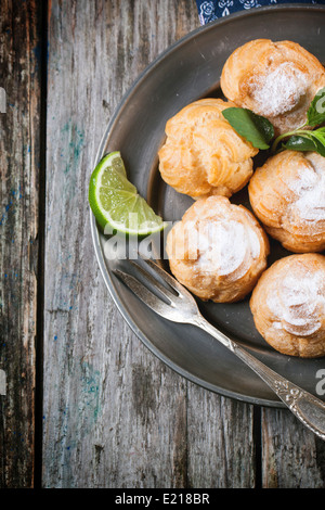 Vintage Teller mit hausgemachten Kuchen Windbeutel auf alten Holztisch. Ansicht von oben. Stockfoto