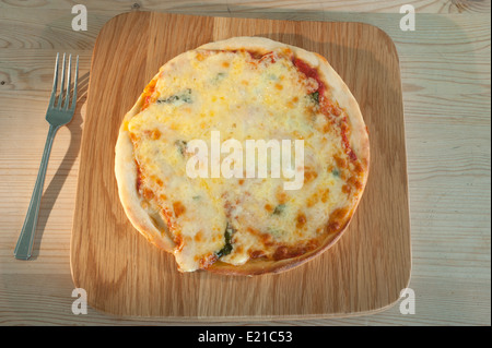 Pizza auf einem hölzernen Teller serviert. Margherita mit Tomaten-Mozzarella-Käse und Basilikum. Stockfoto