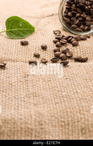 Kaffeebohnen in Glas auf braune Sackleinen Stockfoto
