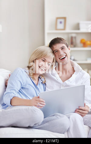 Junges Paar mit Laptop zu Hause lachen Stockfoto