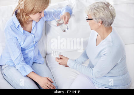 Reife Frau gibt eine junge Frau-Pillen Stockfoto