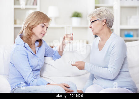 Reife Frau gibt eine junge Frau-Pillen Stockfoto