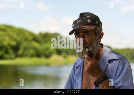 Älterer Mann mit einem Americana patriotischen Hut und Bart an den Ufern des Flusses St.Johns in Zentral-Florida, USA Stockfoto