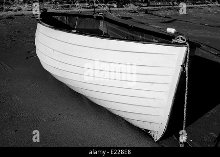 Ein schwarz / weißes Bild eines traditionellen Ruderbootes gefesselt am sandigen Strand von St Ives in Cornwall, Großbritannien. Stockfoto