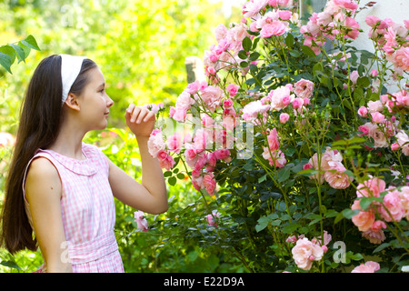 Teenager-Mädchen in der Landschaftsgarten mit blühenden Rosenstrauch Stockfoto