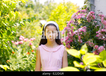 Teenager-Mädchen in der Landschaftsgarten mit blühenden Rosenstrauch Stockfoto