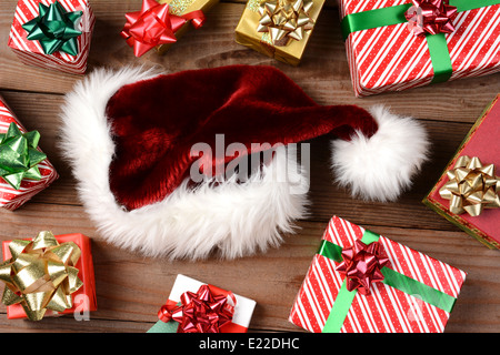 Draufsicht auf eine Weihnachtsmütze umgeben von Weihnachten präsentiert auf einem rustikalen Holzboden. Querformat, füllen der Rahmen. Stockfoto