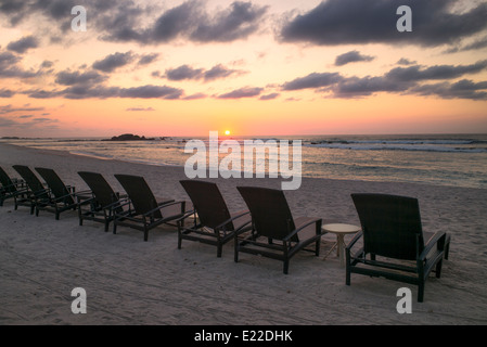 Sonnenuntergang am Strand mit Strandkörben in Punta Mita, Mexiko. Stockfoto