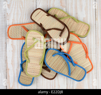 Hohen Winkel Schuss aus einer Gruppe von Sommer Strandsandale auf einem Holzdeck. Die Multi-farbigen Sandalen sind in einem zufälligen Stapel angeordnet. Stockfoto