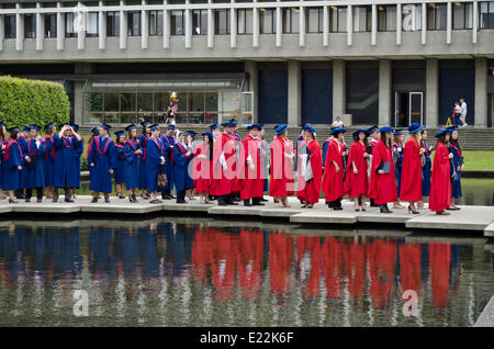 Simon Fraser University diplomanden vor der Frühjahrstagung Einberufung Zeremonie 2014 warten durch Teich in der Akademischen Viereck auf dem Burnaby Campus. Die rote Kleider werden von Ph.D. Empfänger getragen. Stockfoto
