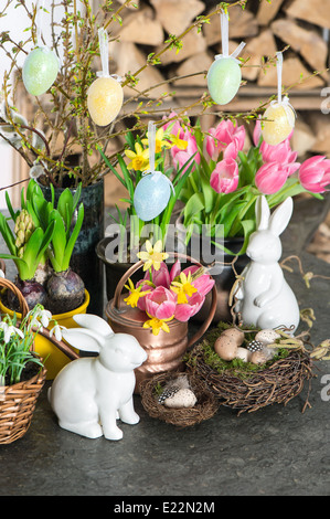 Frühlingsblumen mit Hasen und Eiern Osterdekoration. Tulpen, Schneeglöckchen und Narzissen-Blüten. selektiven Fokus Stockfoto