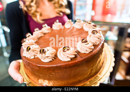 Weibliche Konditor präsentiert Tablett mit Kuchen in der Bäckerei oder Konditorei Stockfoto