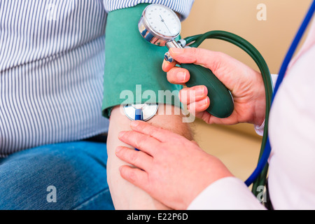 Frau, die Steuerung von Blutdruck mit Stethoskop und Manschette am Arm des Mannes Stockfoto