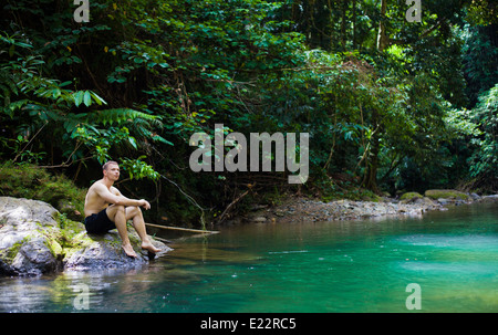 Mann sitzt Dschungel Pool im üppigen immergrünen Regenwald Khao Sok Nationalpark in Thailand. Stockfoto