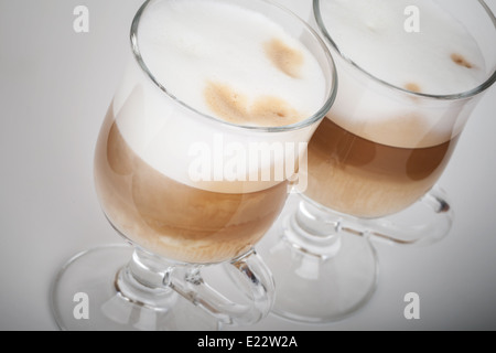 Zwei Glas Becher mit Griffen von Latte Kaffee auf grauem Hintergrund Stockfoto