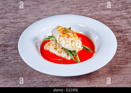 Filet vom Barsch mit Gemüse und Soße serviert auf einem weißen Teller in einem restaurant Stockfoto