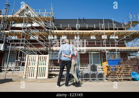 Junges Paar Blick auf neu gebauten Häuser auf Baumaschinen Stockfoto